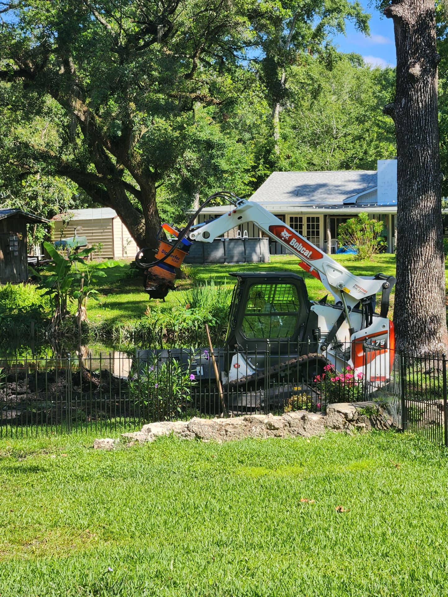 Bobcat loader with Dipperfox SC600 stump grinder on a pond bank