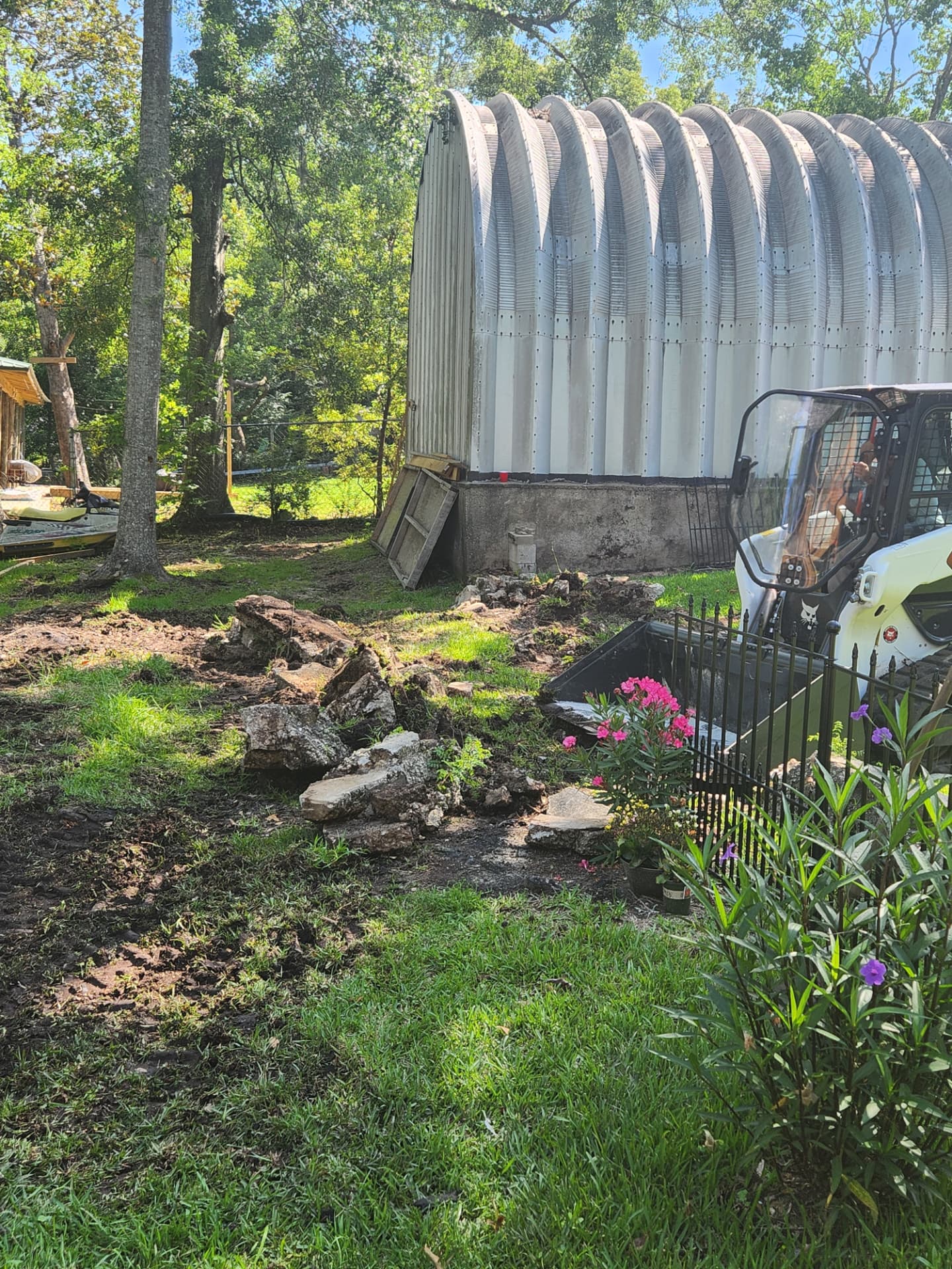 Loader bucket clearing old concrete and debris near a metal building
