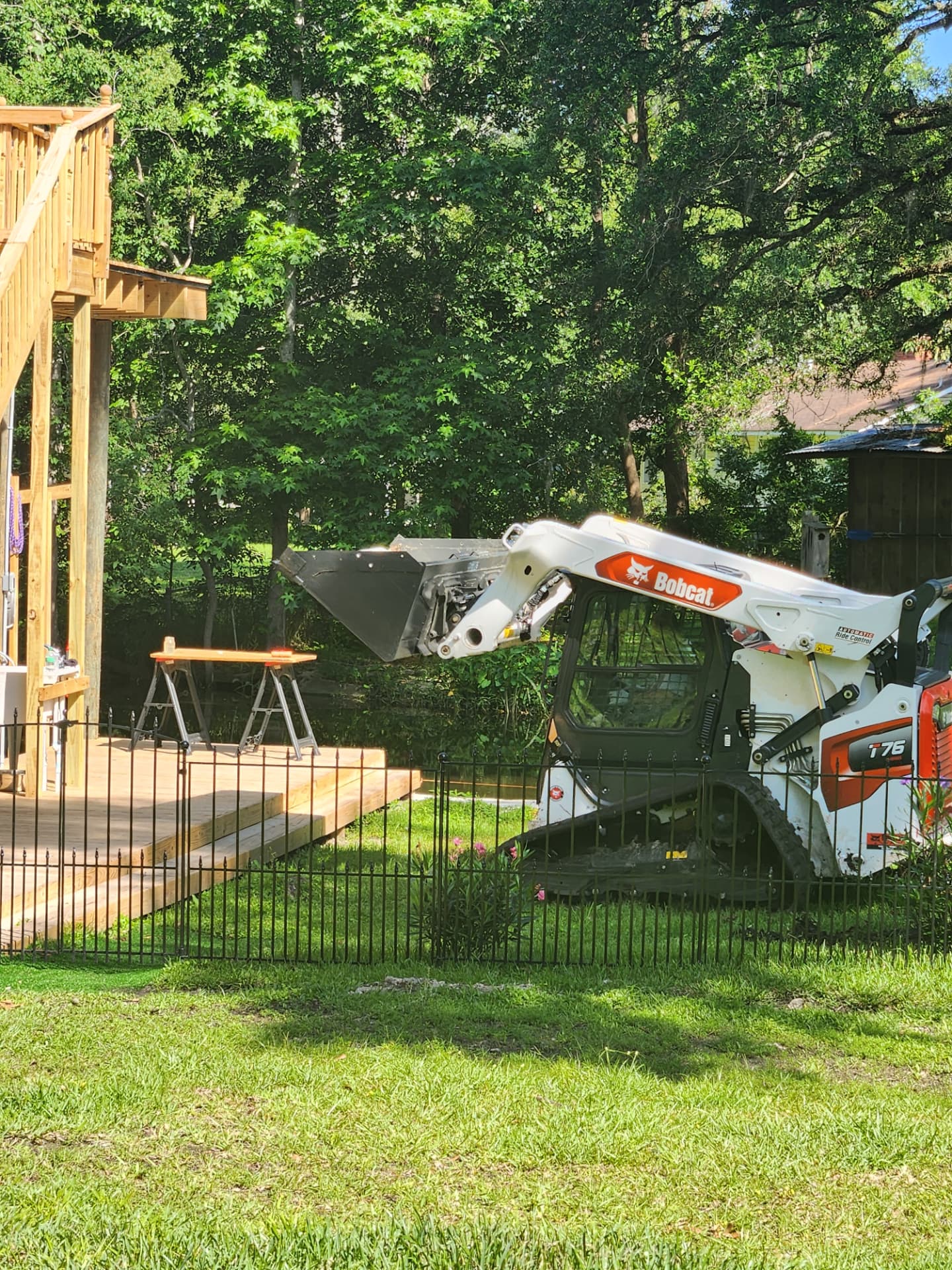 Track loader working next to a new wooden deck without damaging the lawn