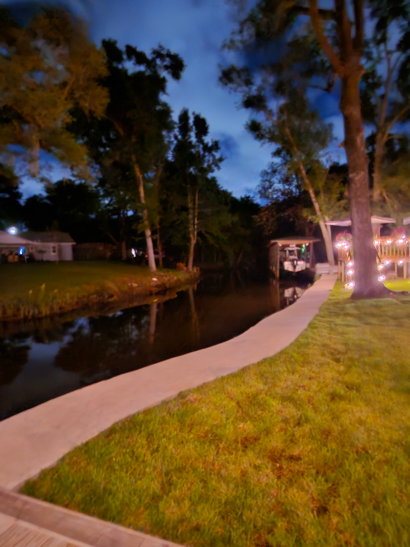 Finished concrete walkway along a canal bulkhead with string lights