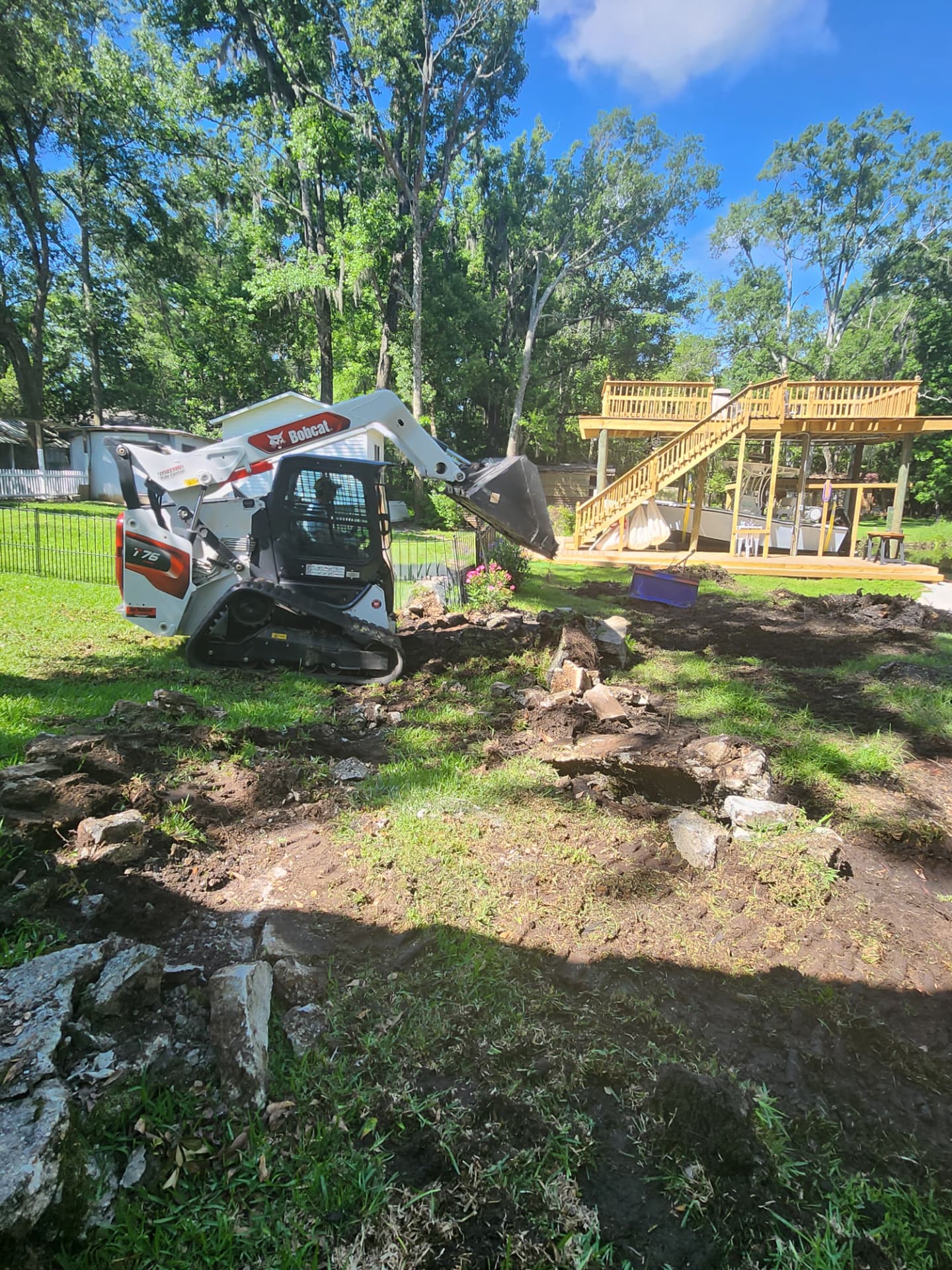 Loader grading and cleanup near a wooden deck