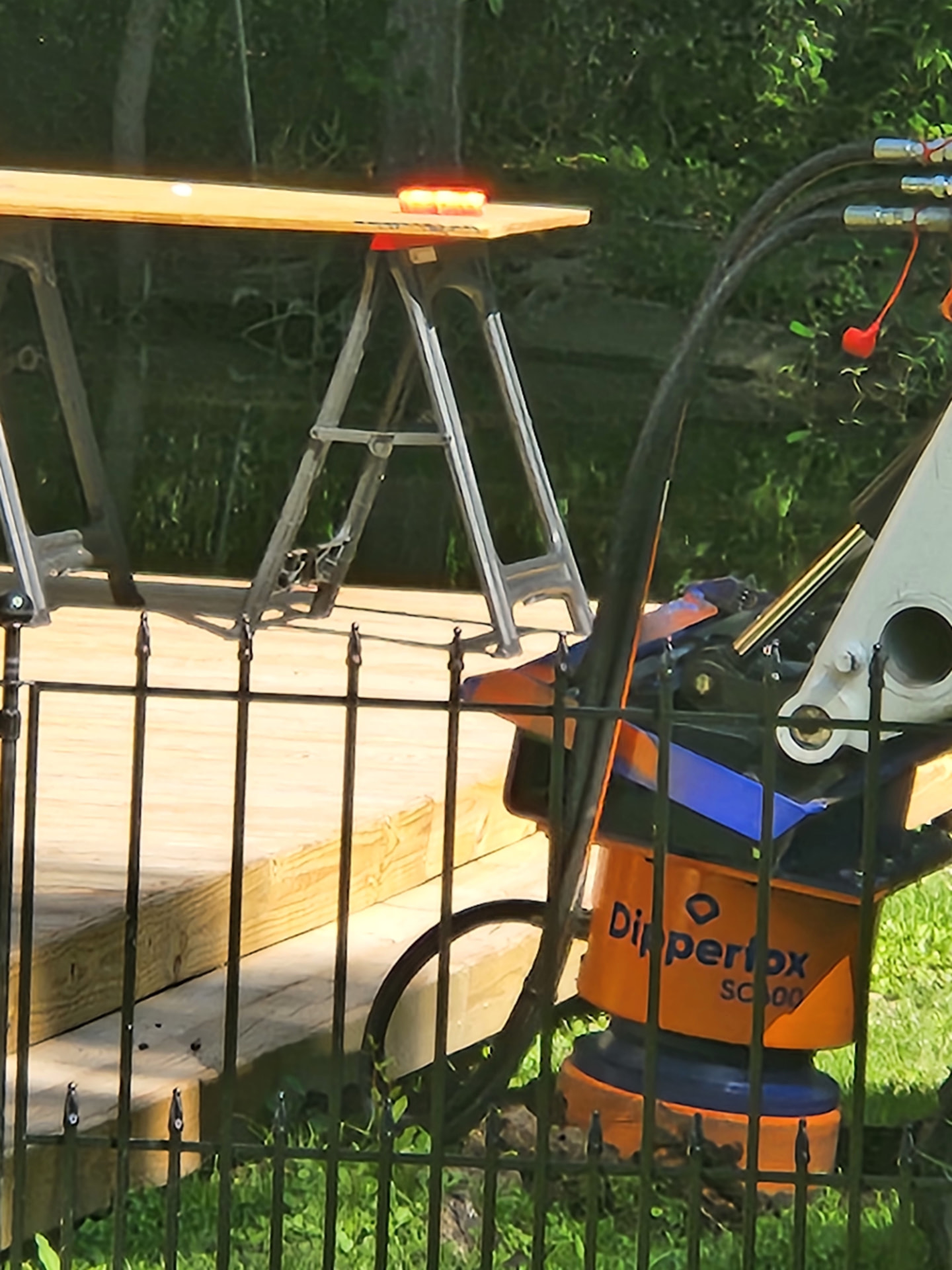 Dipperfox stump grinder attachment near a wooden structure