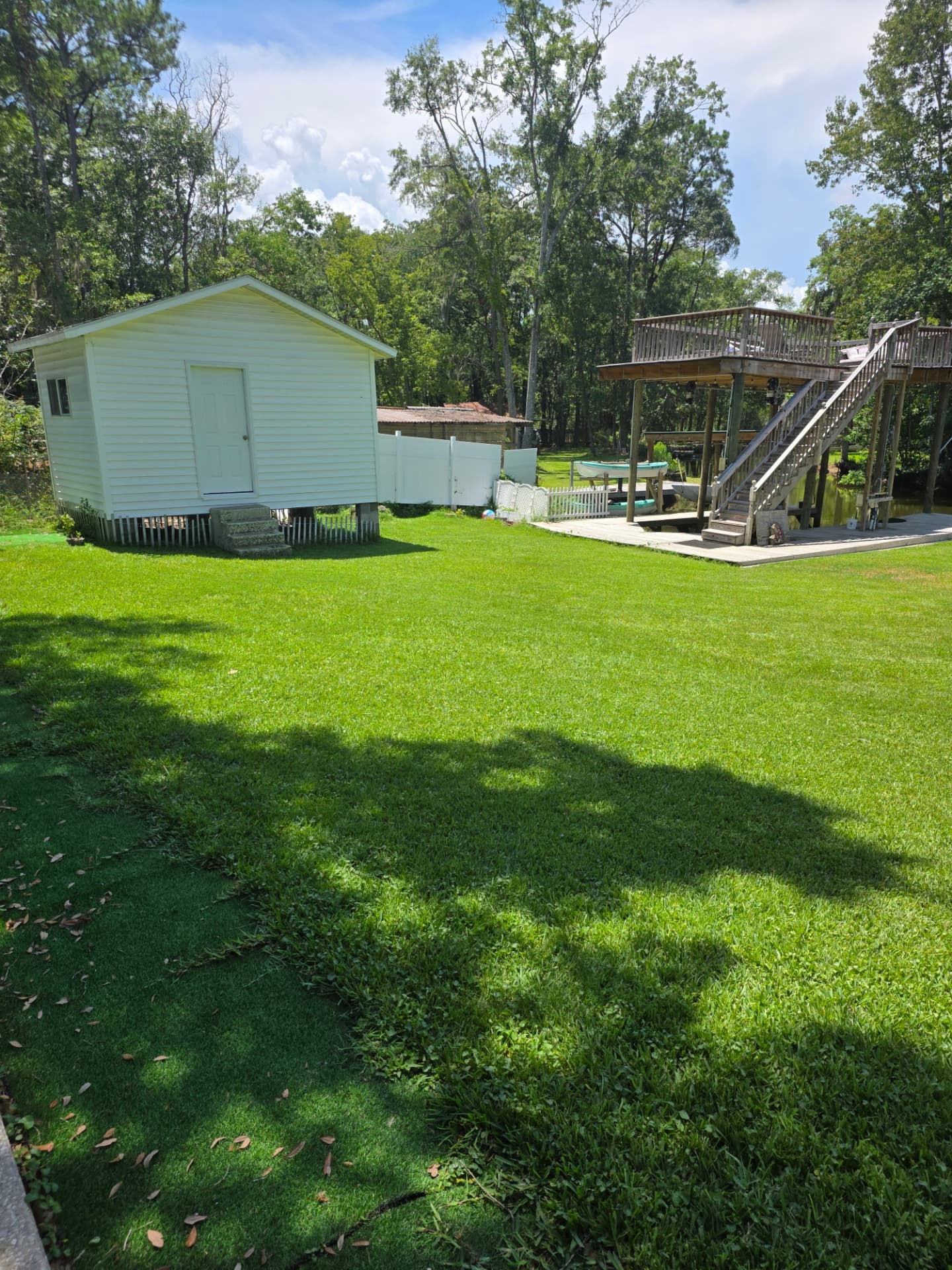 Finished green lawn with a white shed and dock