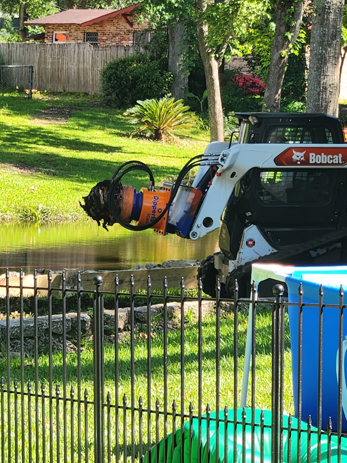 Dipperfox attachment holding a large stump pulled from a pond bank