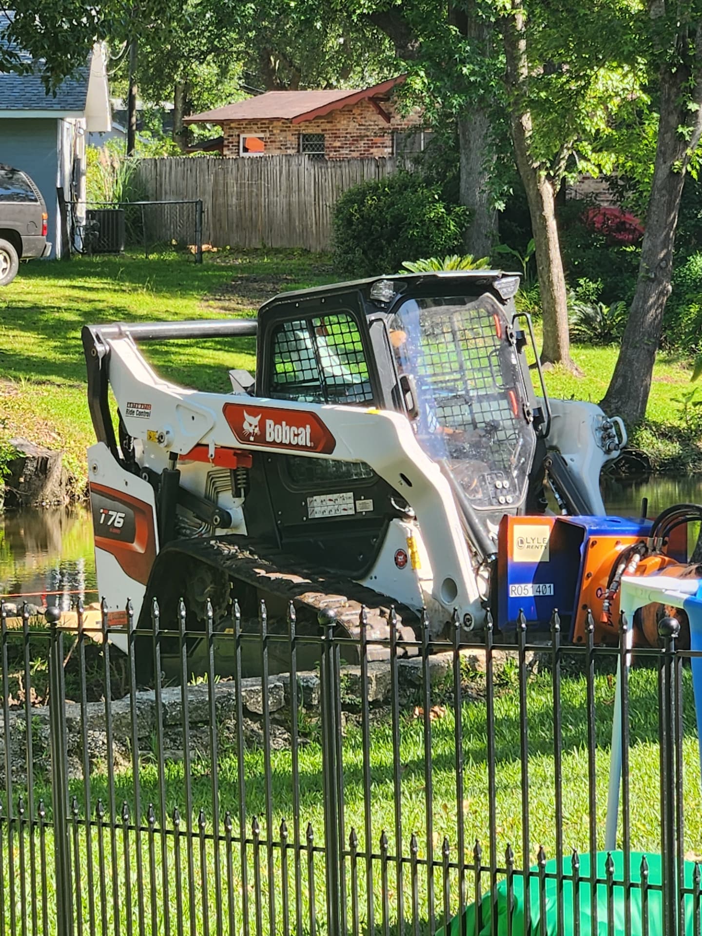 Bobcat T76 with blue and orange attachment staged by the water